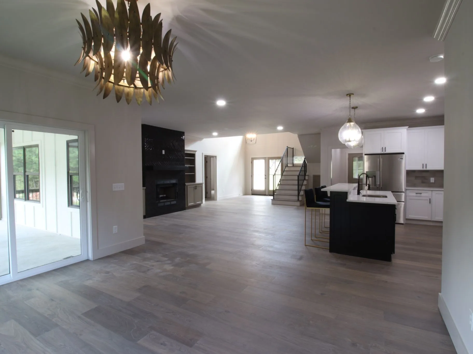 Completed JC T1 open living space with kitchen, fireplace, staircase, and wood-look flooring