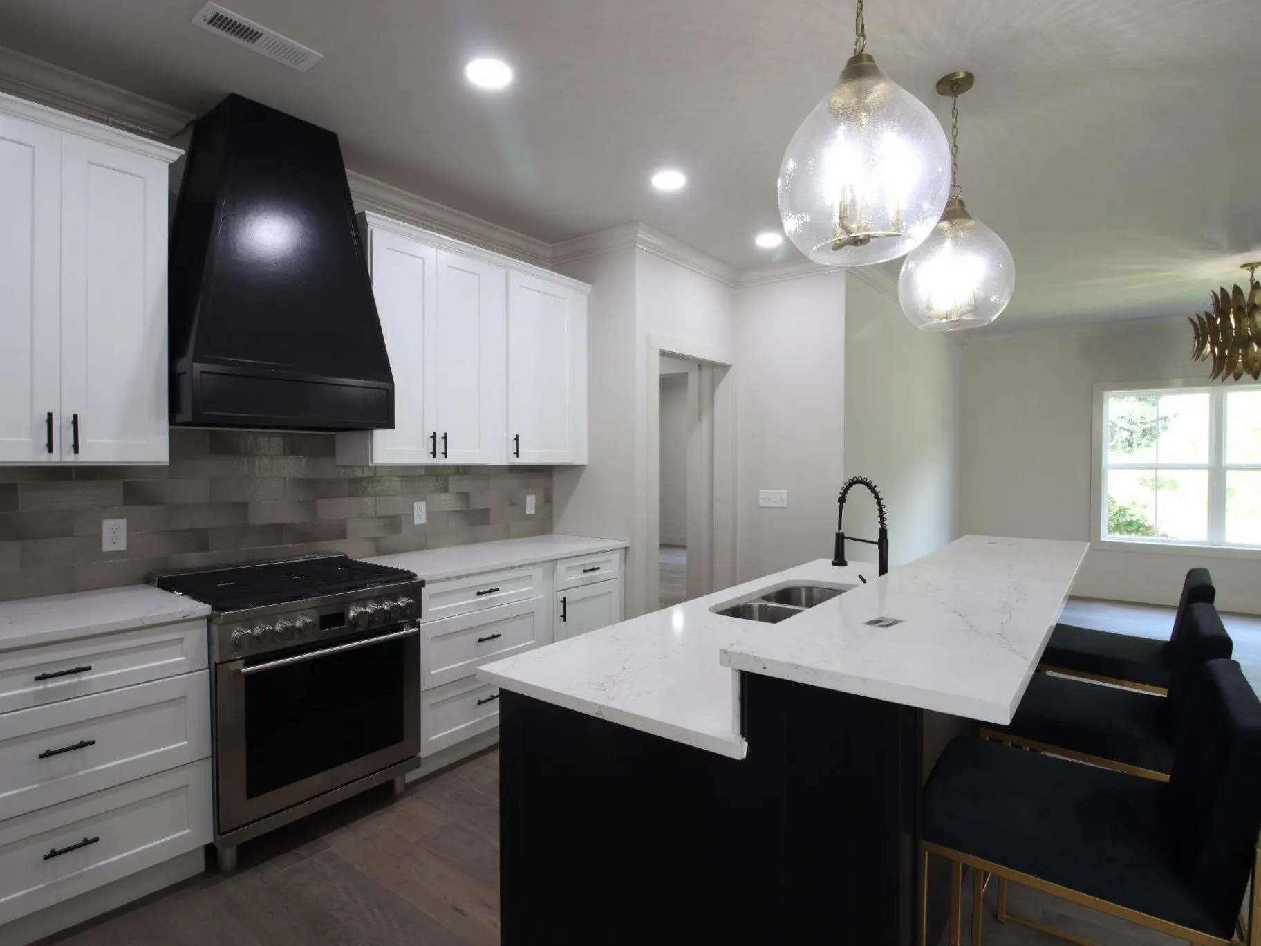 Completed JC T1 kitchen with white custom-made cabinets, dark island, quartz counters, and glass pendants