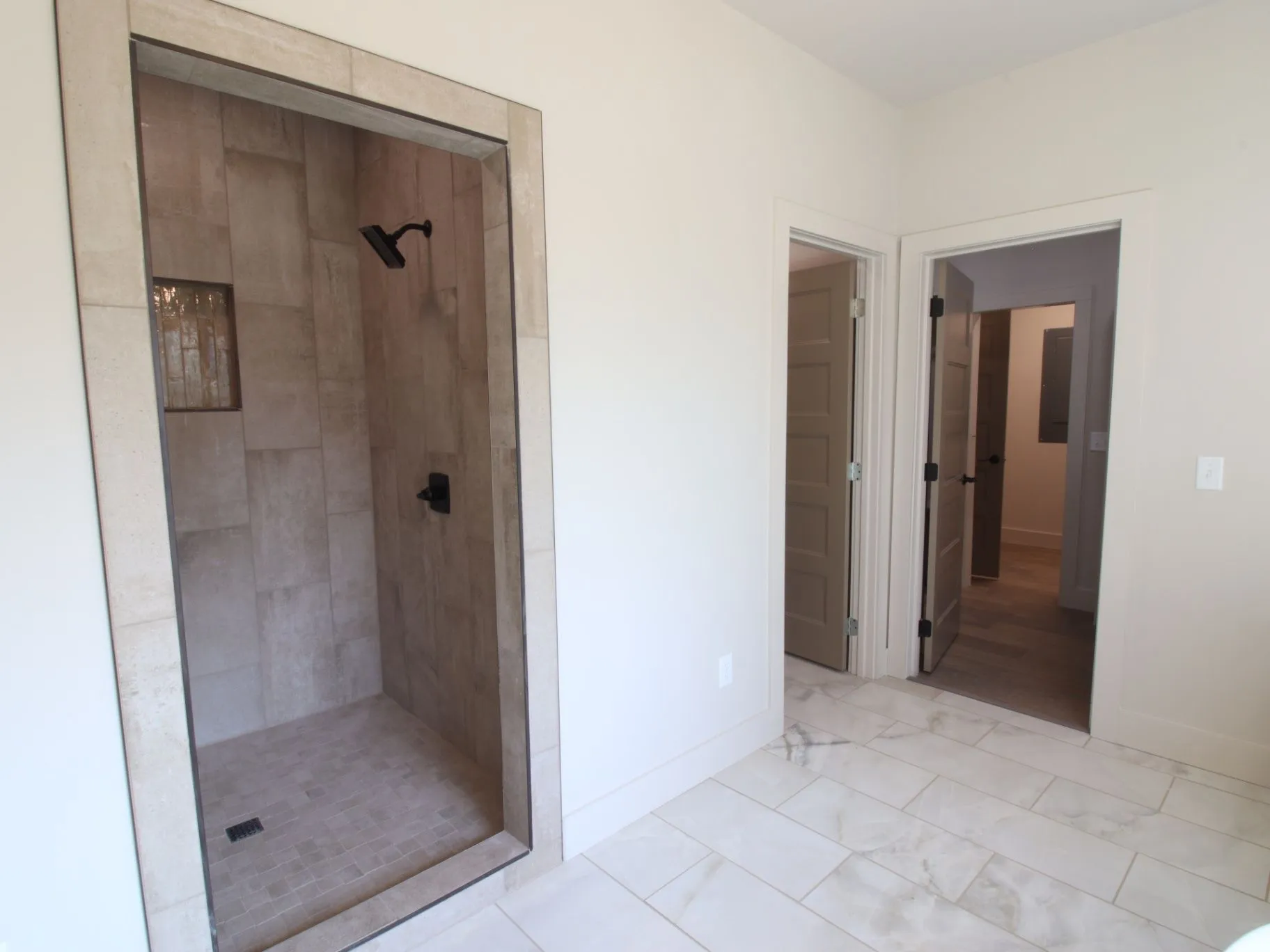 Completed JC T1 custom shower with tiled walls, framed opening, and dark fixtures