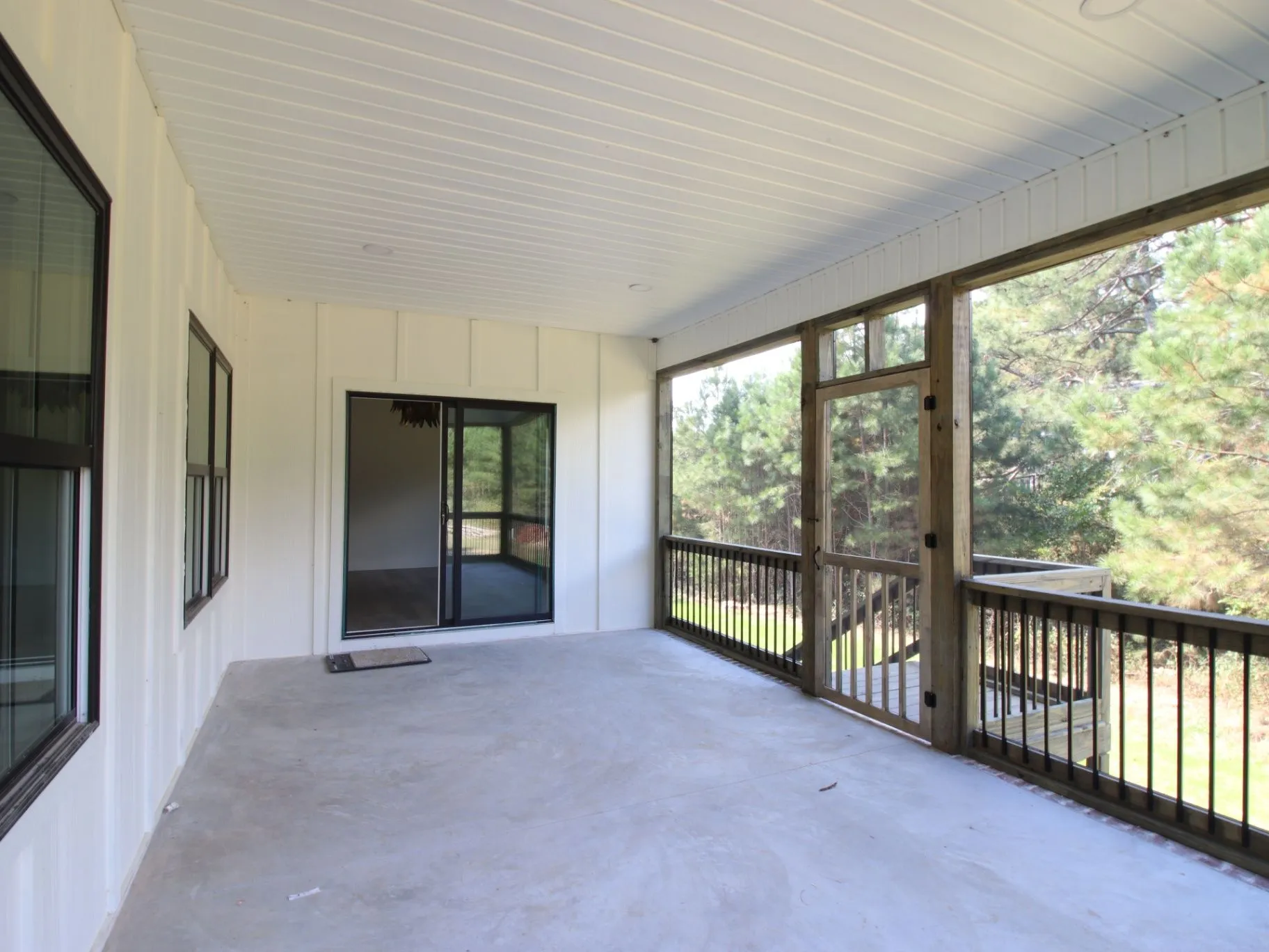 Completed JC T1 covered porch with screened openings, white ceiling, and wooded view