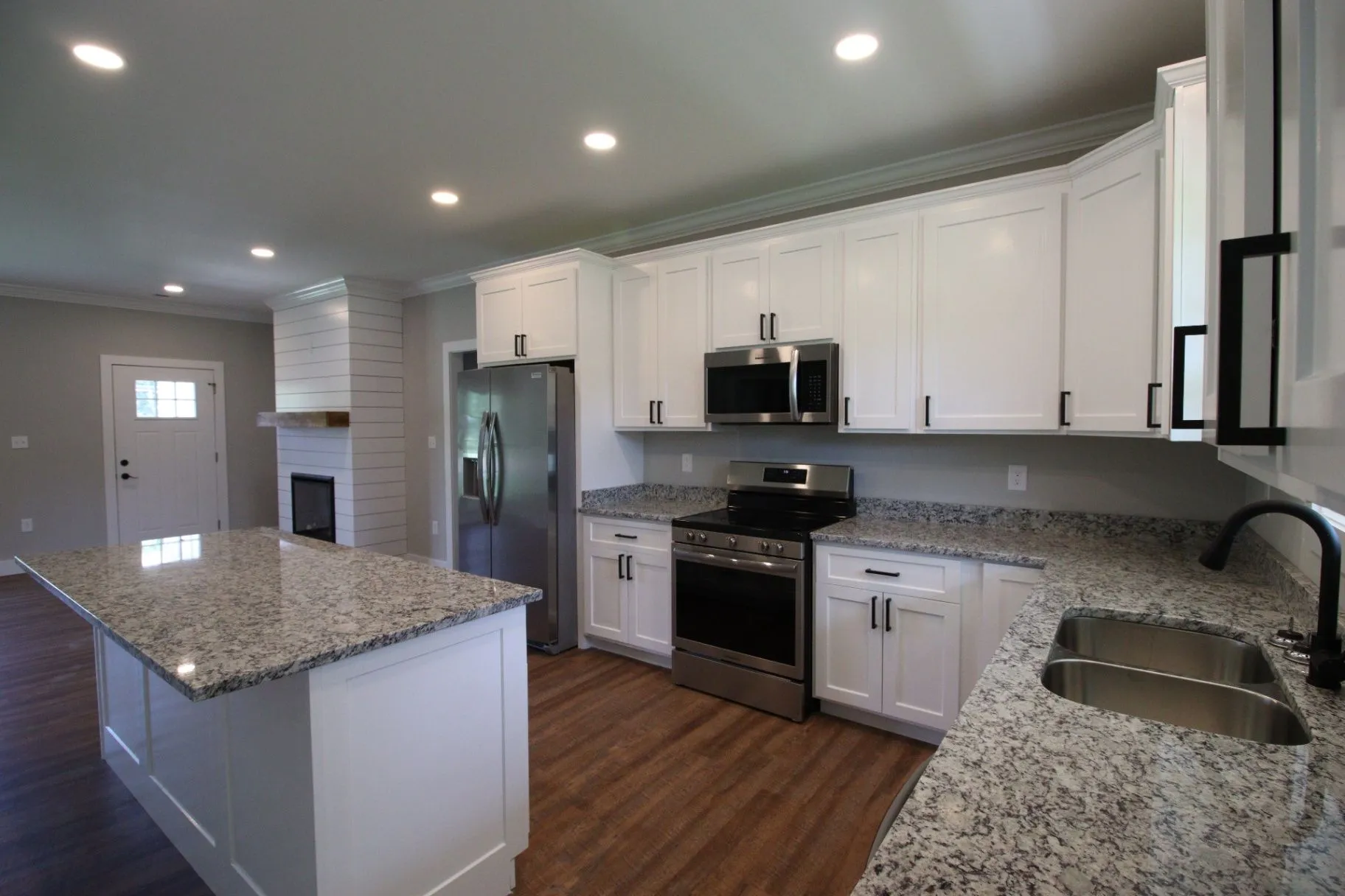 Completed JP2 New Construction kitchen with white cabinetry, granite counters, and a central island